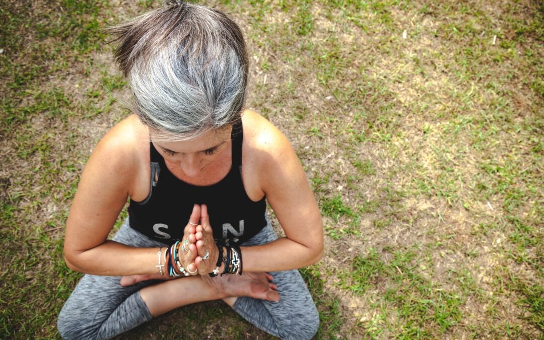 woman in black tank top and gray denim jeans sitting on green grass field during daytime